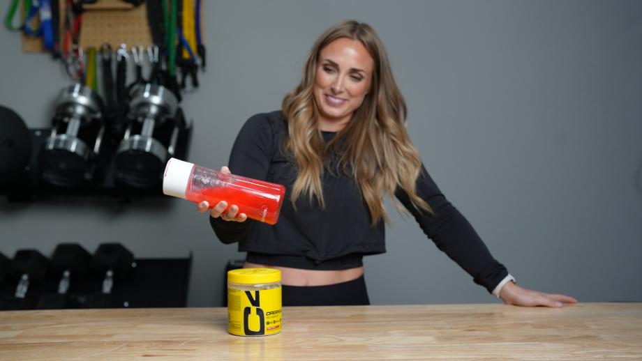 A woman shakes a bottle of water mixed with C4 Pre-Workout