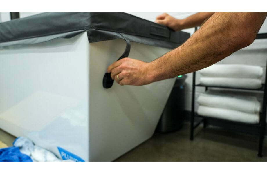 Person securing insulated cover over the Cold Plunge tub