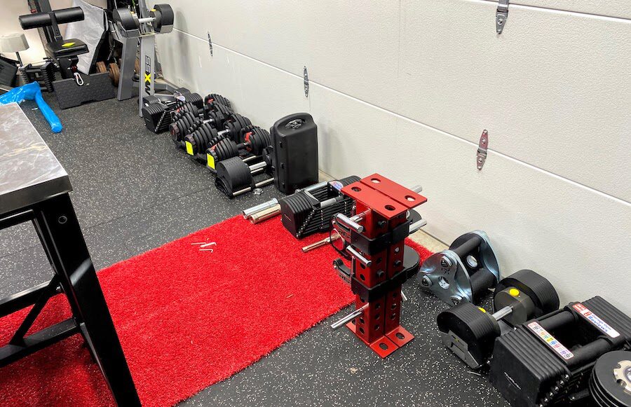 Row of adjustable dumbbells lined up by a wall