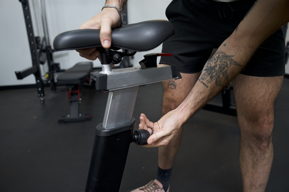 Man adjusting the seat height on the Fringe Sport Raptor Air Bike