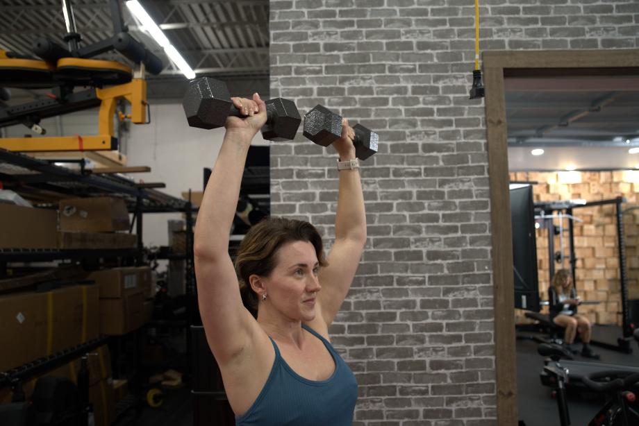 A woman lifting Cap Iron Hex Dumbbells overhead