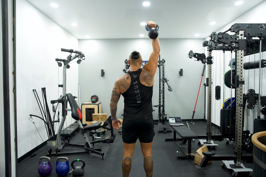 Product tester performing a single-arm overhead press with the Rogue E-Coat kettlebell