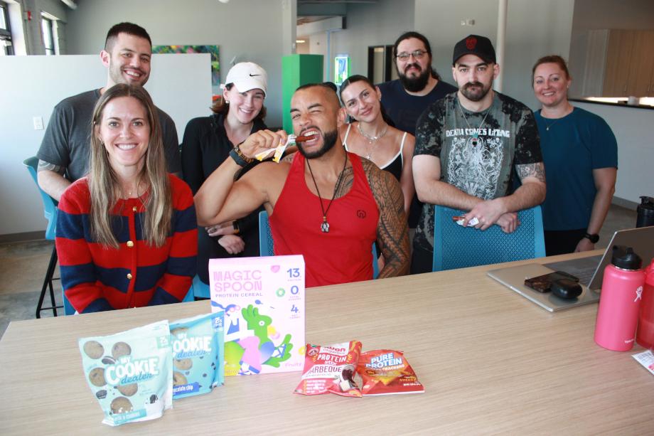 The Garage Gym Reviews team poses for a photo while Stephen Sheehan bites into a 1st Phorm Protein Stick