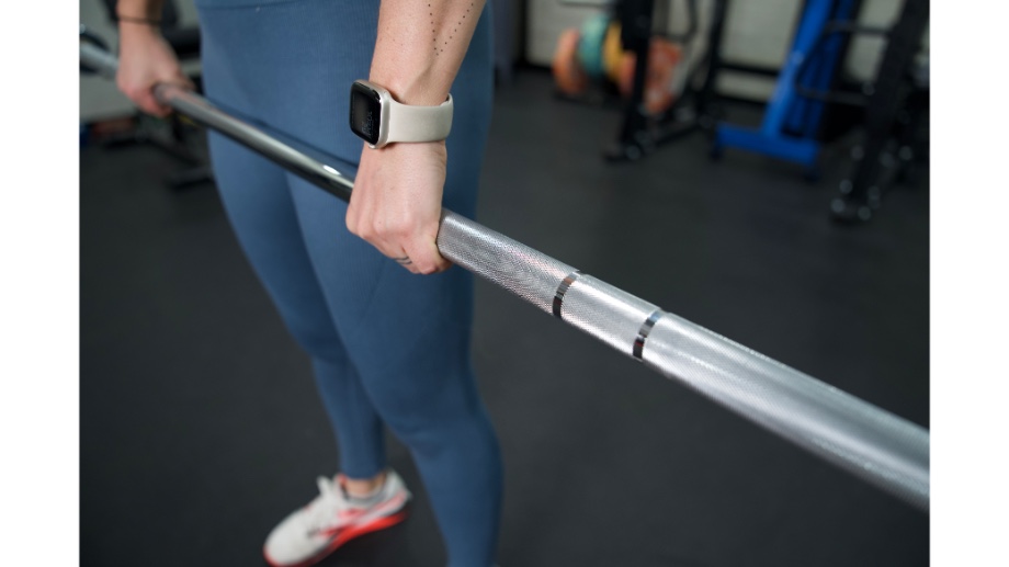 A close up of the knurling on the Major Fitness Barbell while a woman holds the barbell with a deadlift grip