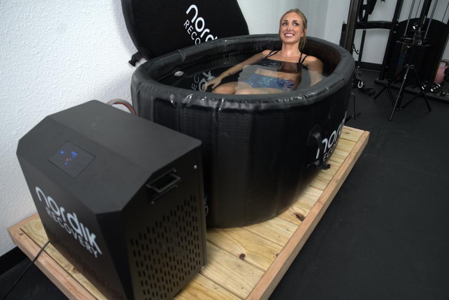 A woman uses the Nordik Recovery Ice Tub and Premium Chiller