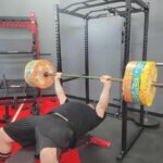 Olympian Caine Wilkes bench pressing with the Giant Lifting Garage Gym Power 2.0 Rack as a spotter
