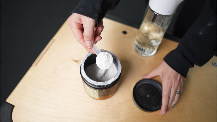 A hand holding a scoop of Optimum Nutrition Gold Standard Pre-Workout