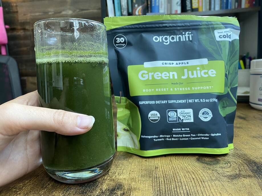 cup with green liquid next to cup of Organifi Green Juice. It's in a clear glass with some green residue on the sides