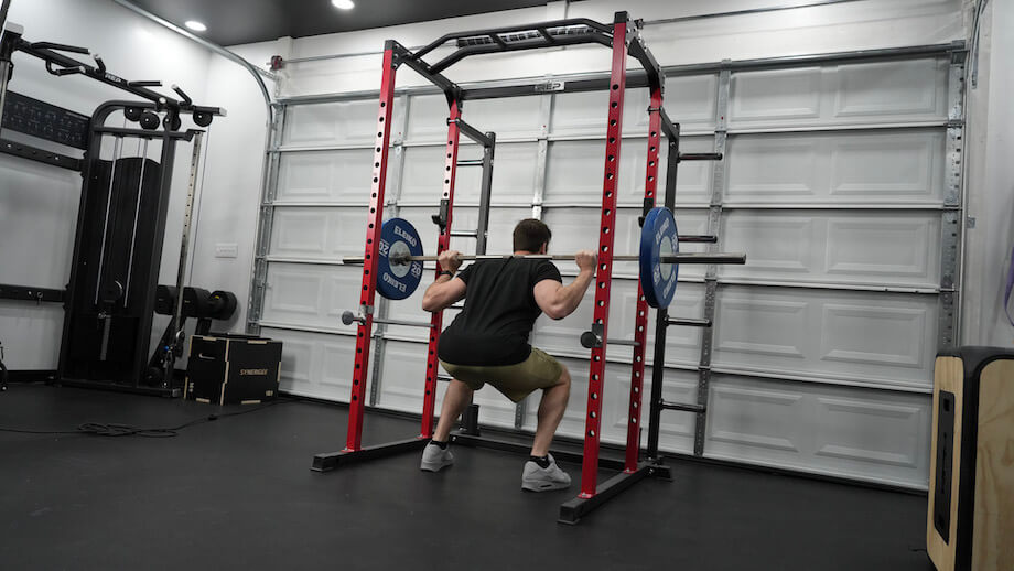 A person performing barbell back squats on the REP PR-1100