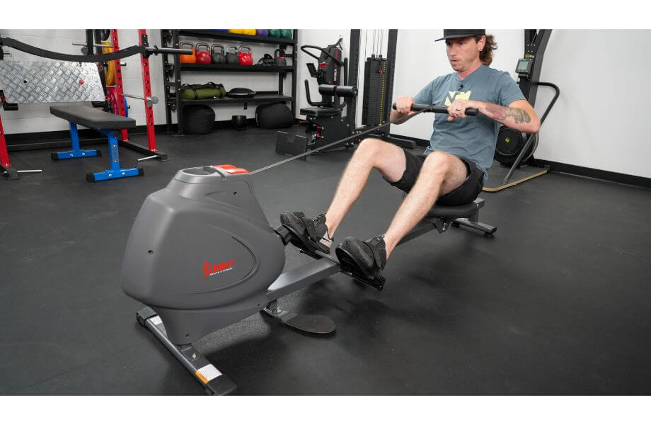A man in a gym setting using a Sunny Health & Fitness SPM Magnetic Rowing Machine