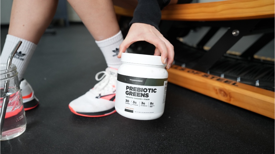 Someone holding a Transparent Labs Prebiotic Greens container near the floor