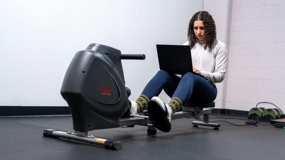 Our tester using a fitness app on a laptop while working out on a rowing machine