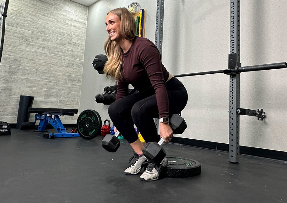 Woman performing a heels-elevated dumbbell hack squat